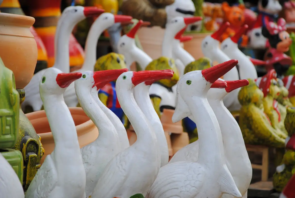 Rows of white ceramic herons with red beaks for sale in Areguá