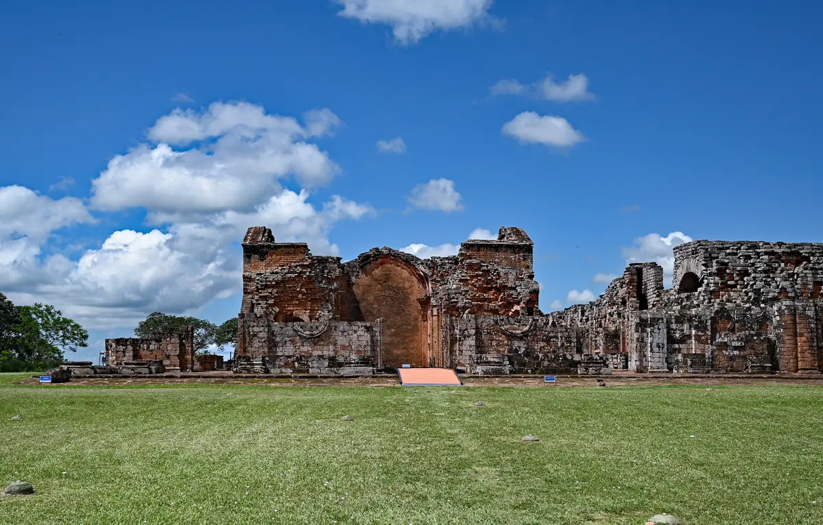 Red stone ruins of the main church at the Jesuit mission of La Santísima Trinidad de Paraná under a blue sky